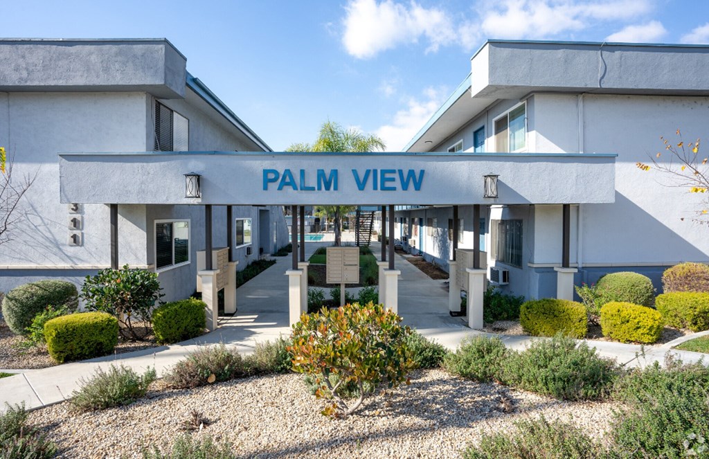 a white building with a blue sign that reads palm view