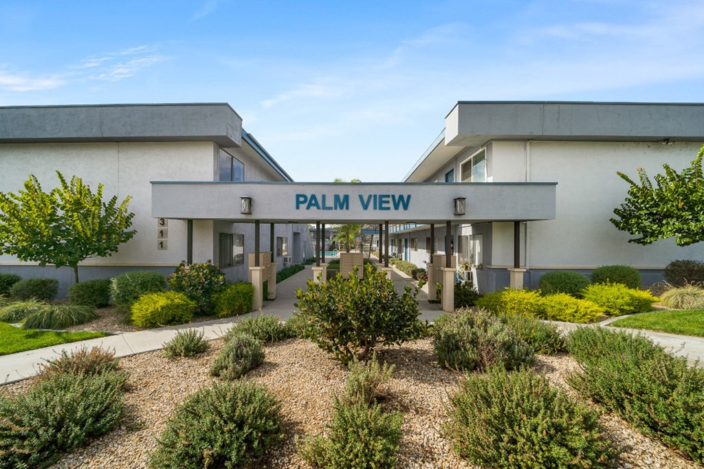 a building with a sign that reads palm view in front of a garden
