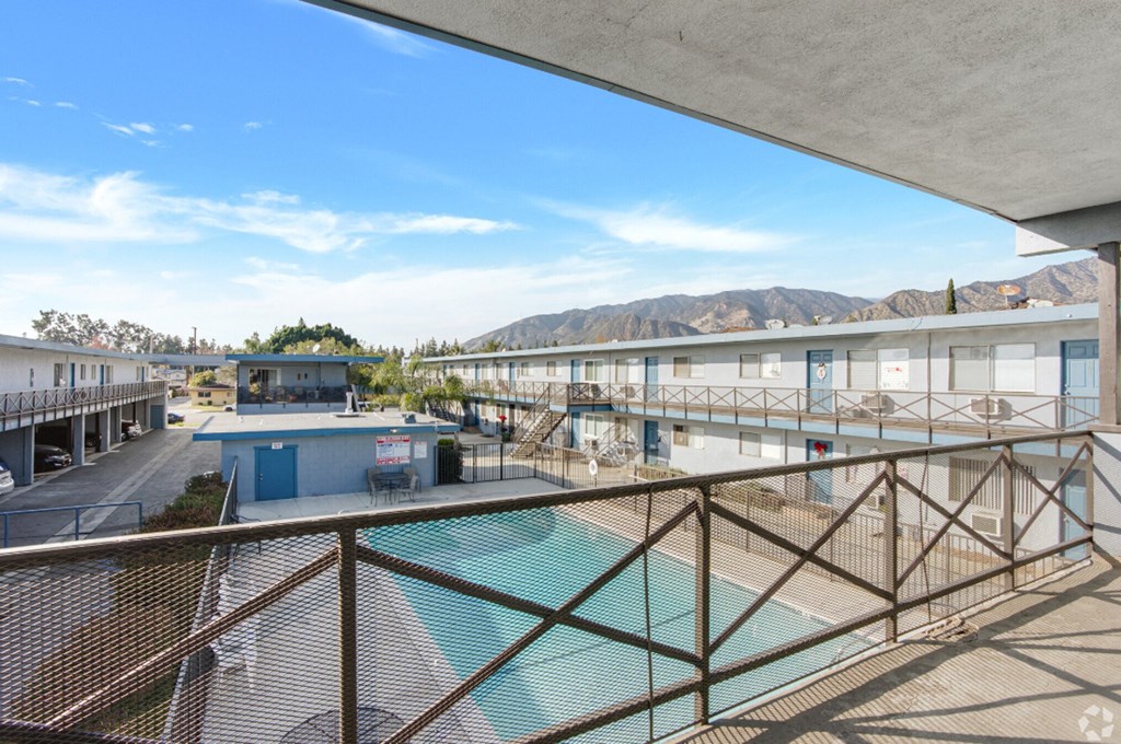 the view of a pool and buildings from a balcony with a view of the mountains