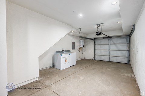 A spacious garage with a white wall and a white washing machine.