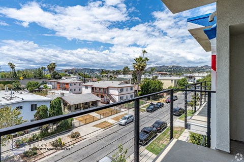 A balcony overlooks a street with cars and houses.