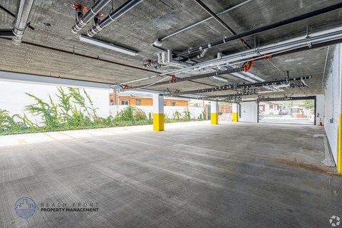 A parking garage with a concrete floor and yellow poles.