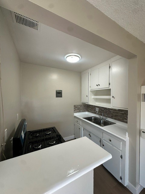 A small kitchen with a white counter top and a black stove.