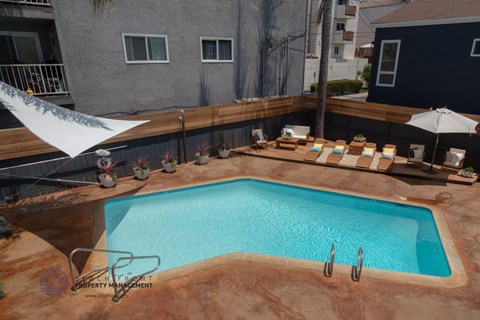 A small pool with a white umbrella and a table with chairs around it.