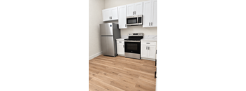A kitchen with a stainless steel refrigerator, microwave, oven, and cabinets.