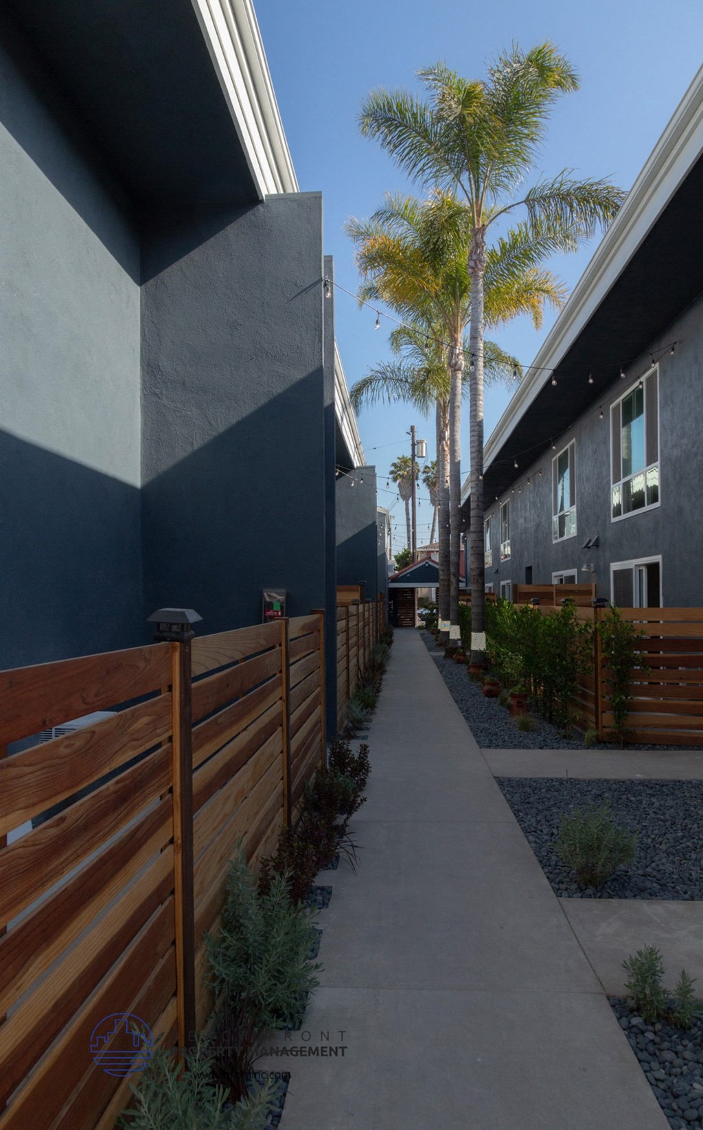 A narrow walkway between two buildings with a wooden fence on the left.