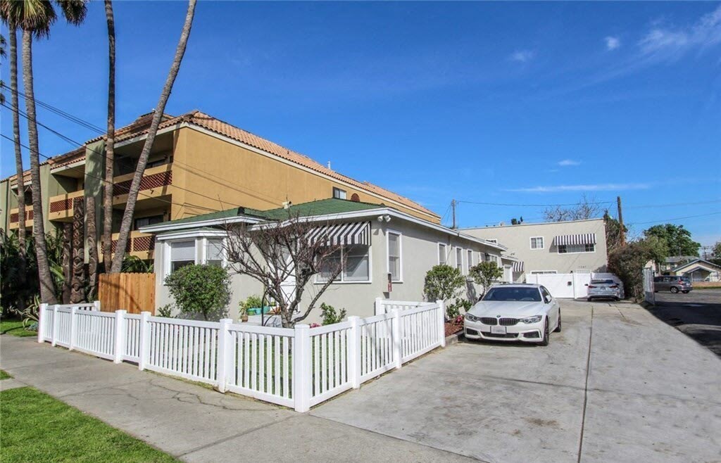 a house with a white fence and a car parked in front of it