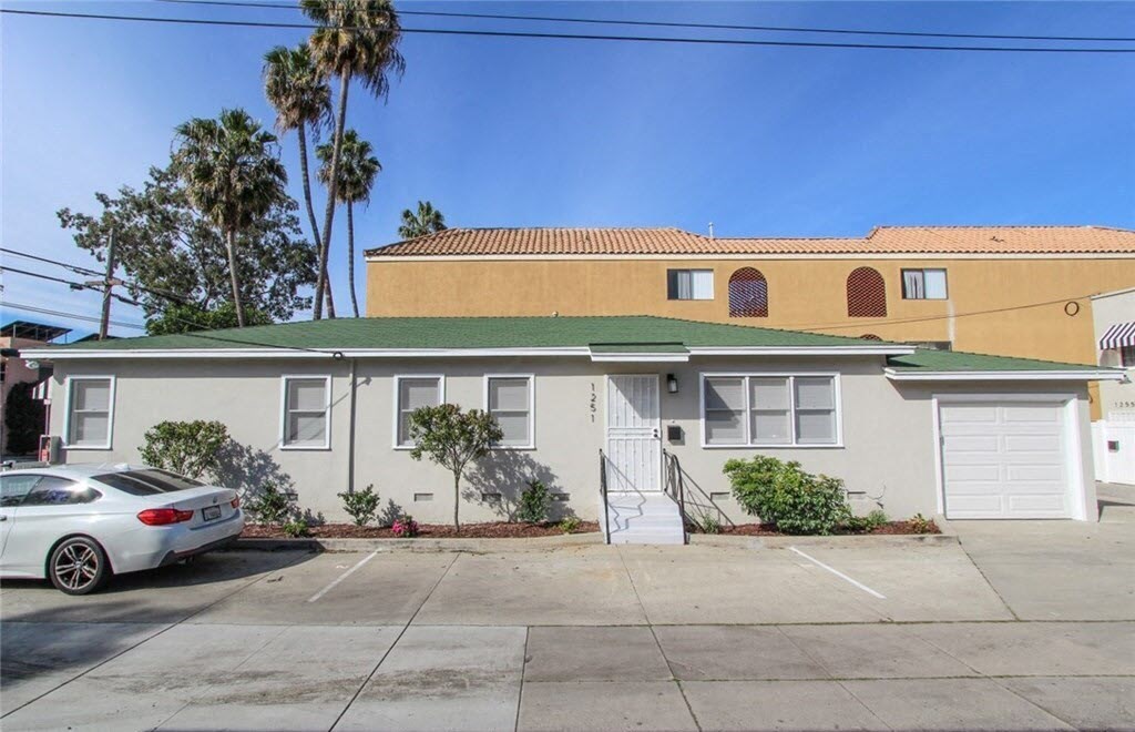a white house with a green roof and a parking lot