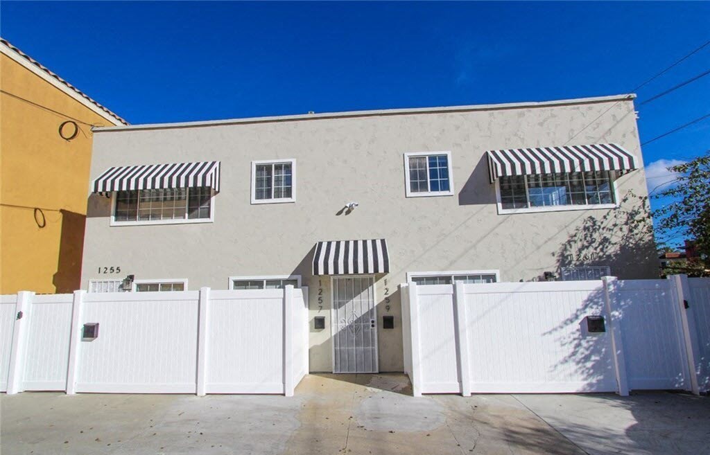 the front of a white house with a white fence
