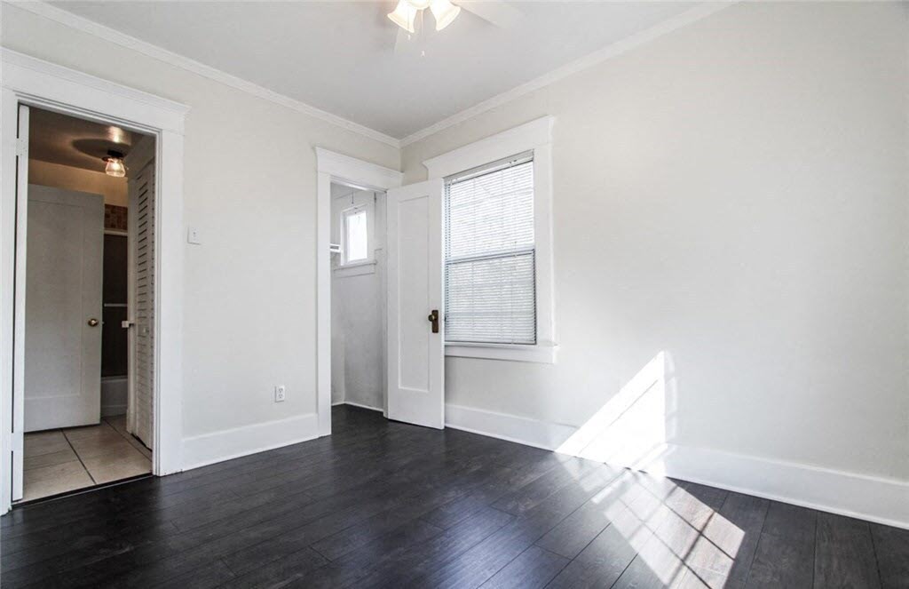 an empty living room with white walls and dark wood floors