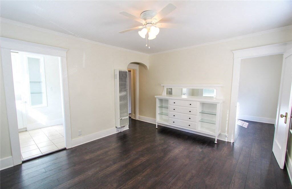 an empty living room with a ceiling fan and a dresser