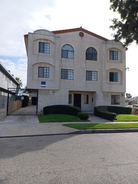 a white building with a sidewalk and a gate