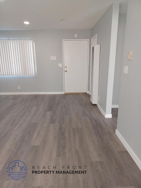 a renovated living room with wood flooring and a white door