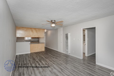 A spacious room with a ceiling fan and wooden flooring.