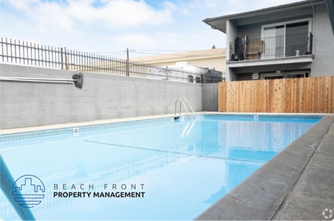 A pool with a fence and a building in the background.