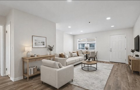 A living room with a white couch, a coffee table, and a television.