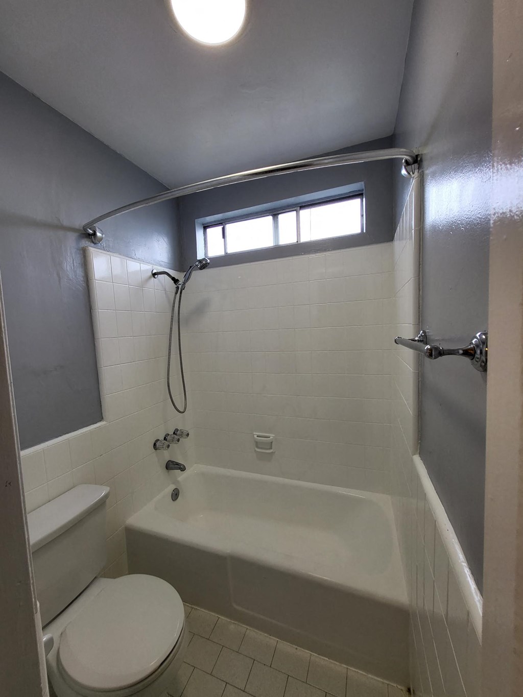 a bathroom with a toilet and a tub and a window