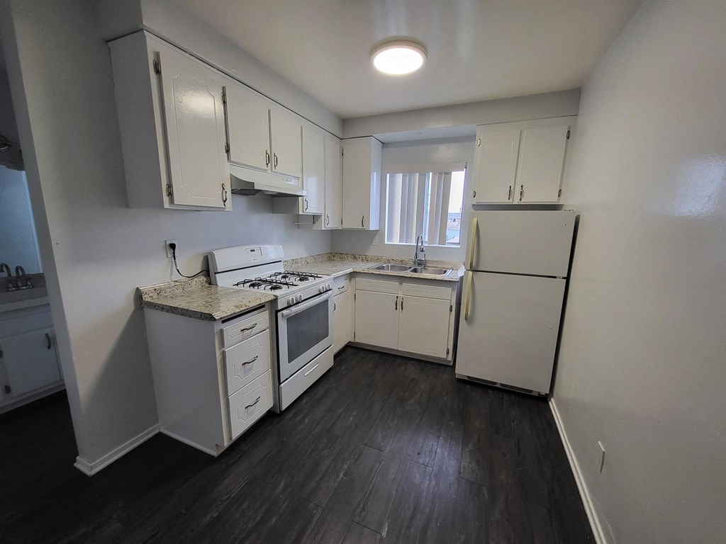 an empty kitchen with white cabinets and a white refrigerator