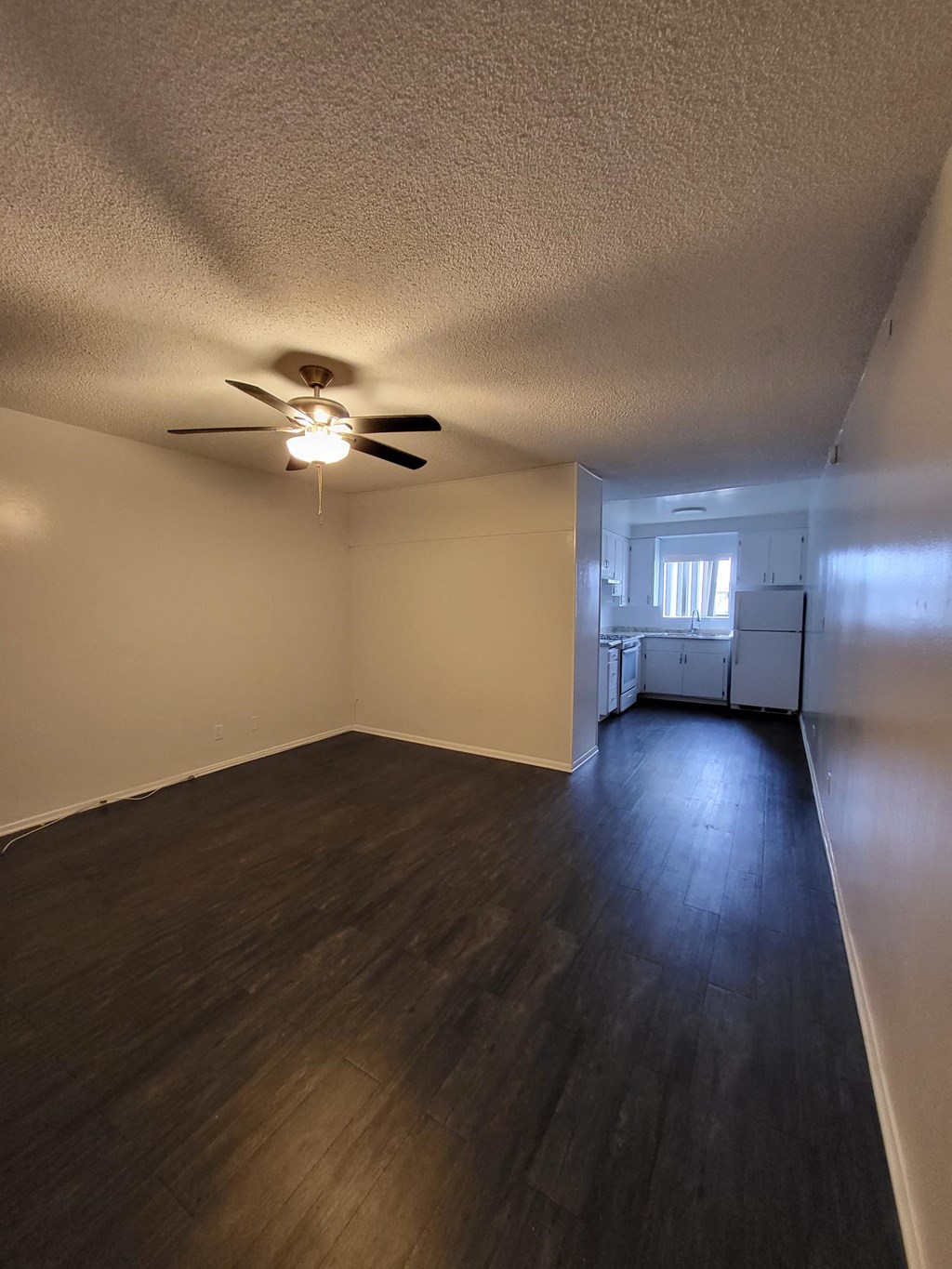 an empty living room with wood floors and a ceiling fan