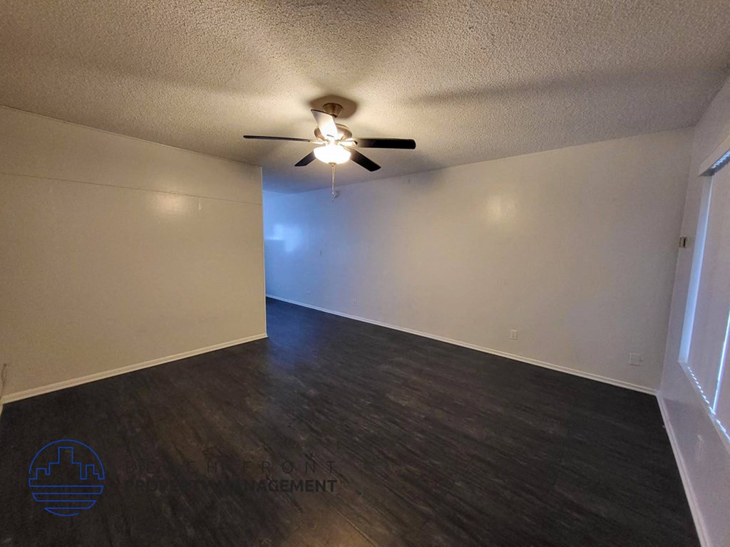 an empty living room with a ceiling fan and wood floors