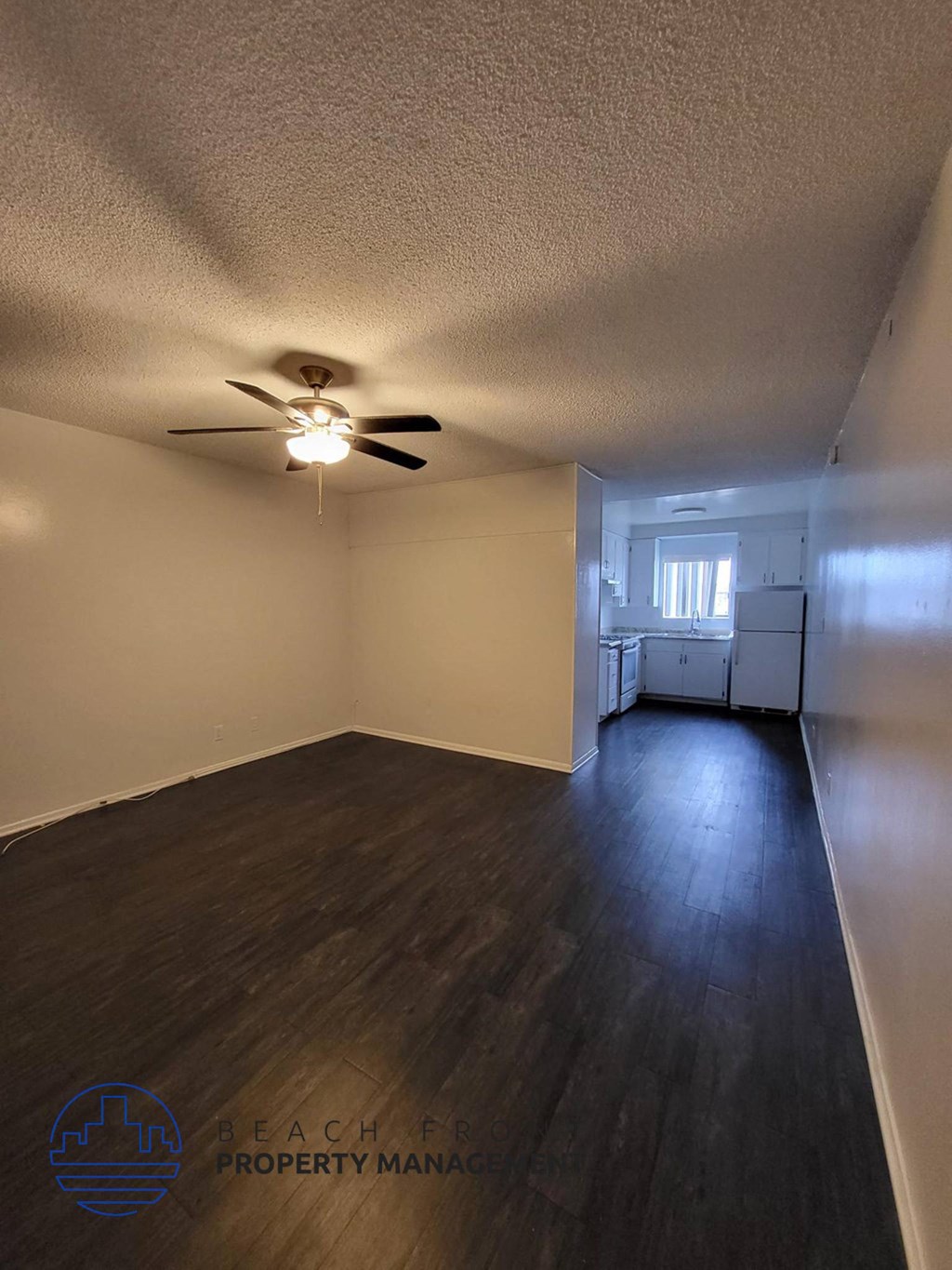an empty living room with a ceiling fan and wood floors