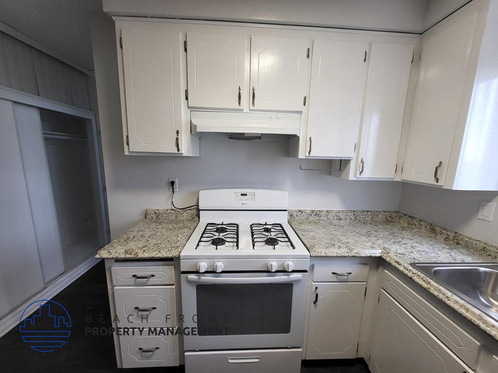 a kitchen with white cabinets and a stove and a sink