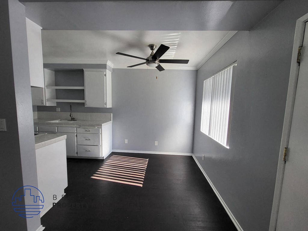 a room with a ceiling fan and a kitchen
