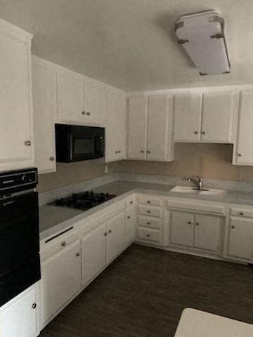 an empty kitchen with white cabinets and black appliances