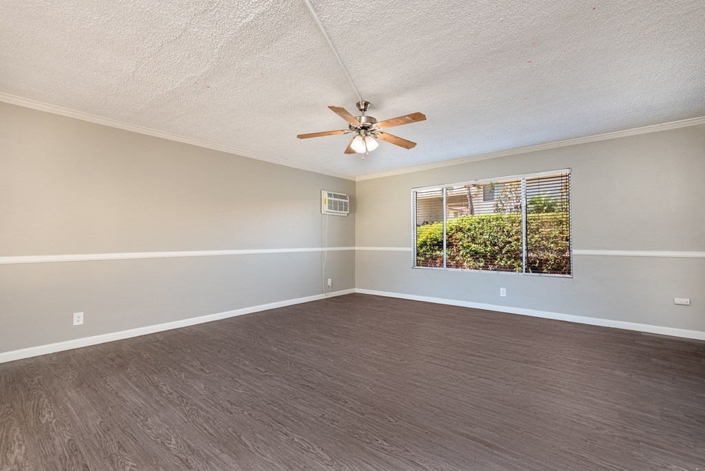 an empty living room with a ceiling fan and a window