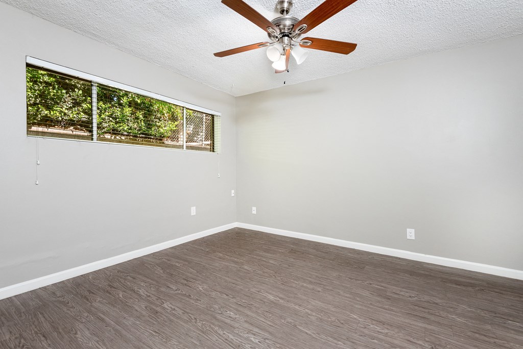 an empty living room with a ceiling fan and a window