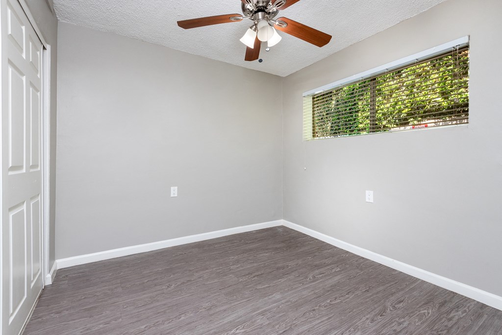 an empty living room with a ceiling fan and a window