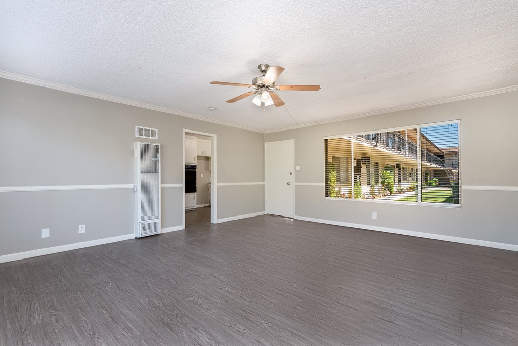 an empty living room with a ceiling fan and a large window