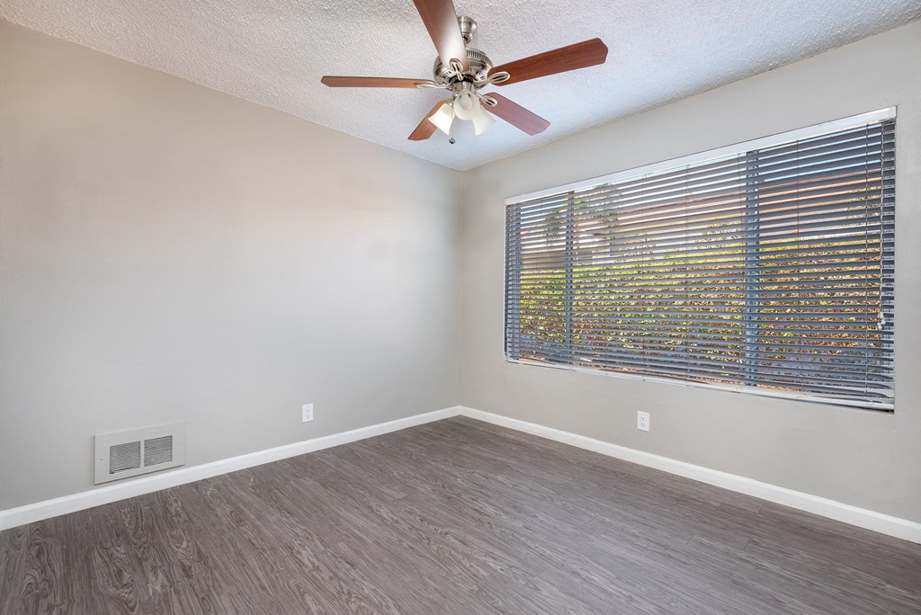 an empty living room with a ceiling fan and a window