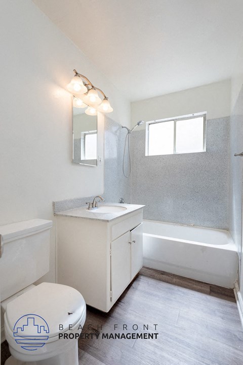 A white bathroom with a toilet, sink, and mirror.