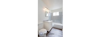A white bathroom with a toilet, sink, and mirror.
