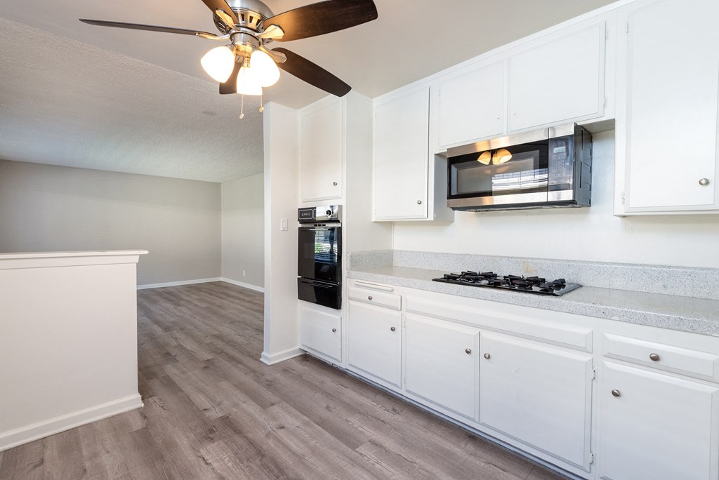 an empty kitchen with white cabinets and a ceiling fan