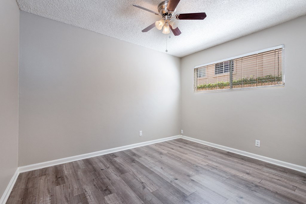 an empty living room with a ceiling fan and a window