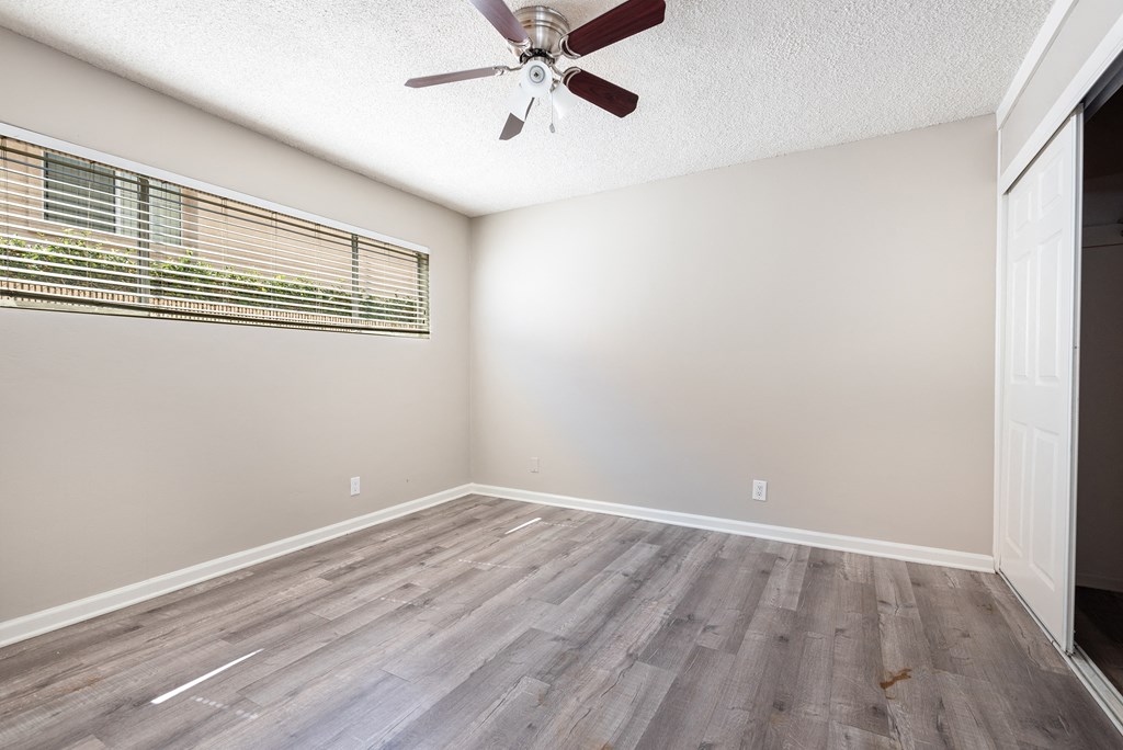 an empty living room with a ceiling fan and a window