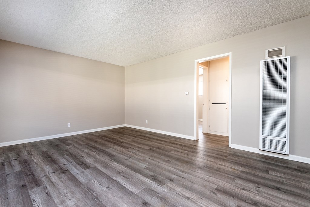 an empty living room with wood flooring and white walls