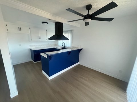 A kitchen with a blue island and a fan.