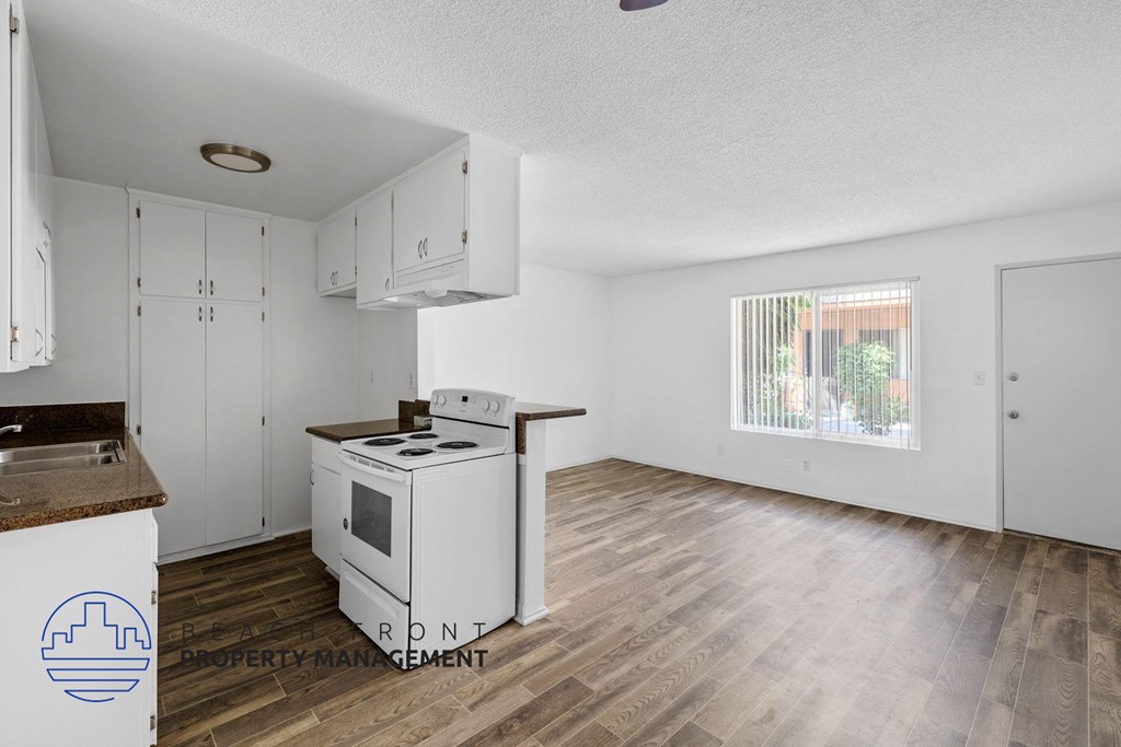 A kitchen with white cabinets and a stove top oven.