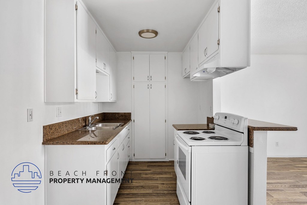 A kitchen with white cabinets and a white stove top oven.
