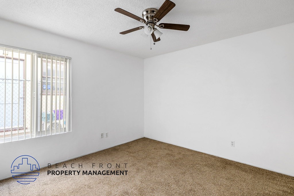 A room with a ceiling fan and a window with blinds.