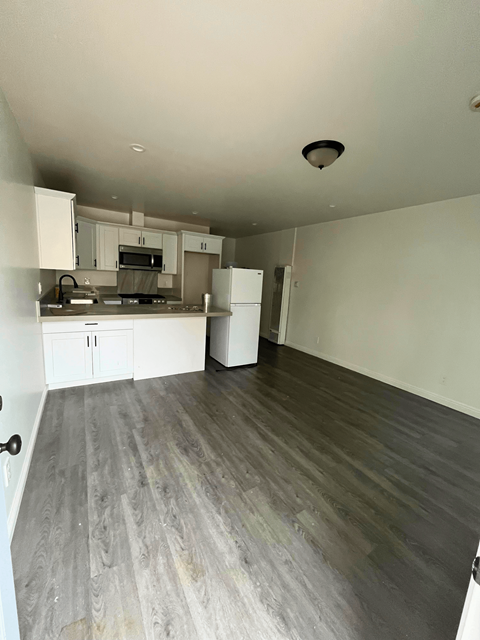 an empty living room and kitchen with wood flooring