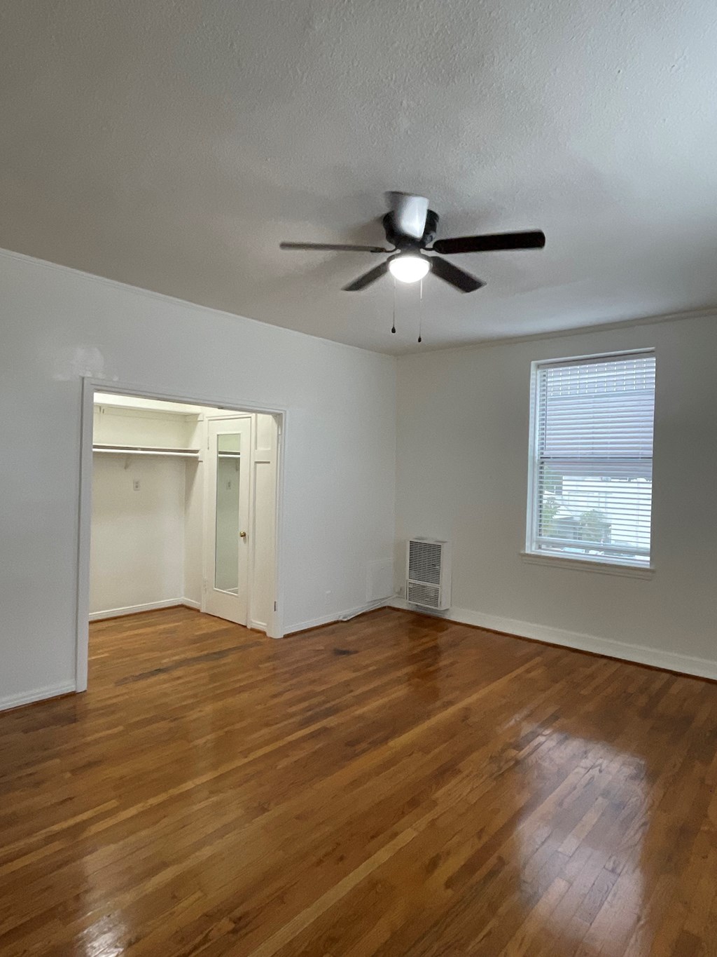 an empty living room with wooden floors and a ceiling fan