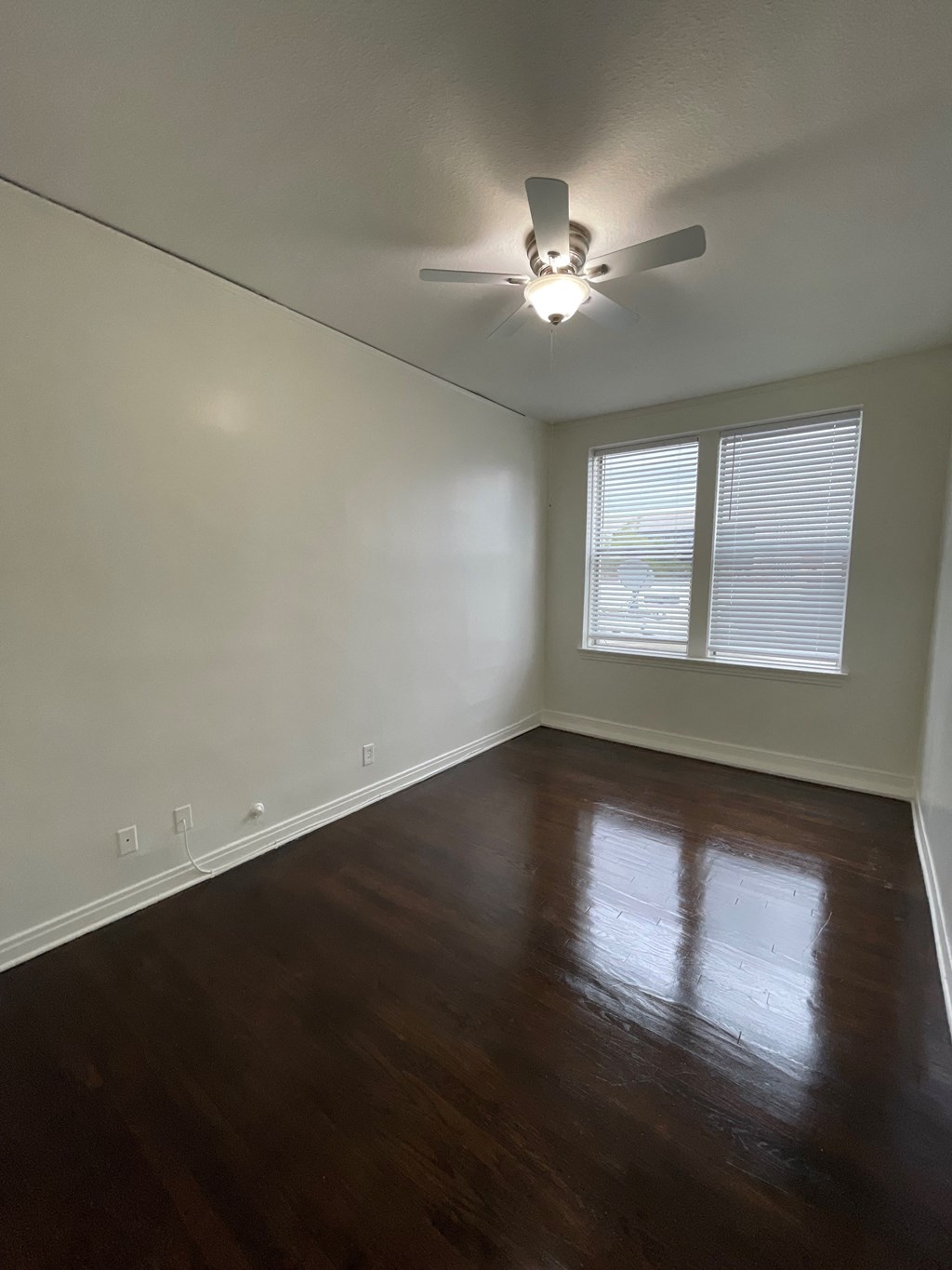 a living room with wood floors and a ceiling fan