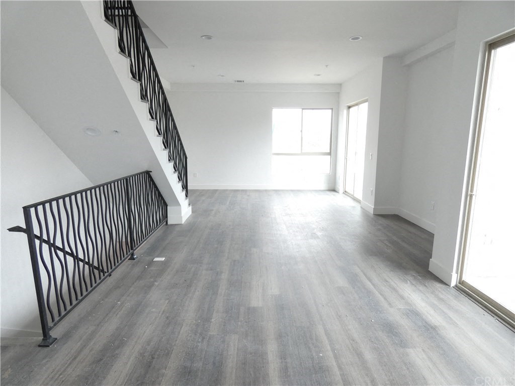 an empty living room with a staircase and white walls and wood flooring