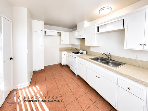 A kitchen with white cabinets and a tiled floor.