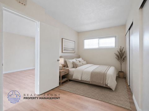 A bedroom with a bed, nightstand, and a plant.