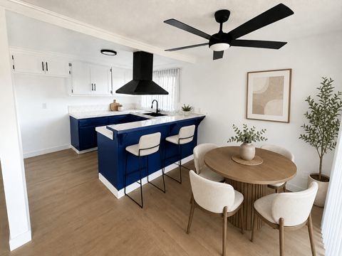 A kitchen with a blue island and white chairs.